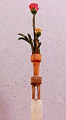 carved matchstick, 2 flowers in a pot on a table